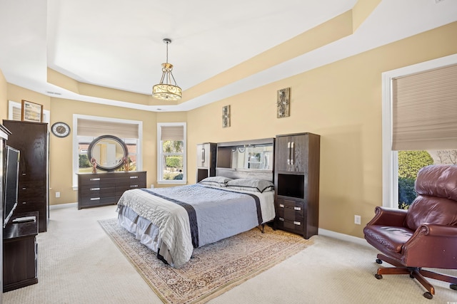 bedroom with baseboards, a raised ceiling, and light carpet