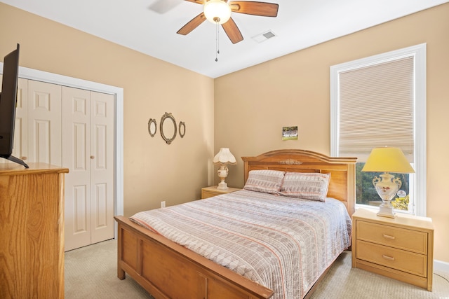 bedroom featuring a closet, visible vents, a ceiling fan, and light colored carpet