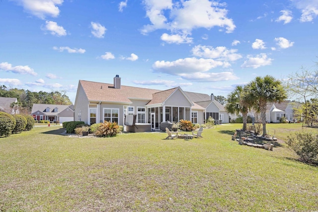 back of house featuring a lawn, a chimney, and a sunroom
