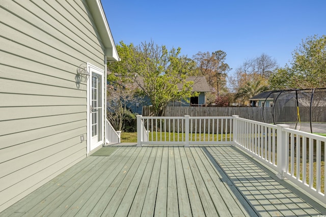 deck featuring a trampoline and a fenced backyard