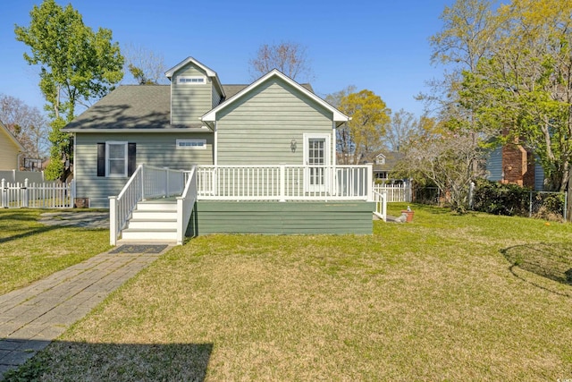 back of property featuring fence, roof with shingles, a deck, and a lawn