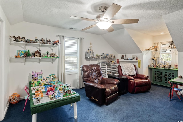 recreation room featuring a textured ceiling, a ceiling fan, carpet flooring, and vaulted ceiling