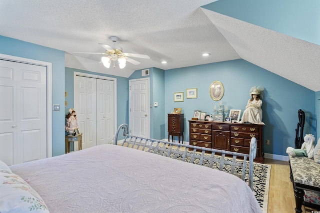 bedroom with wood finished floors, vaulted ceiling, ceiling fan, visible vents, and a textured ceiling