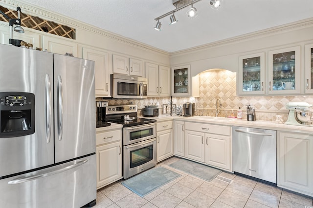 kitchen featuring a sink, stainless steel appliances, light countertops, light tile patterned flooring, and backsplash