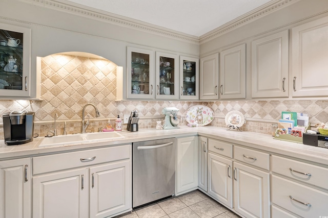 kitchen with a sink, light tile patterned flooring, tasteful backsplash, stainless steel dishwasher, and white cabinets