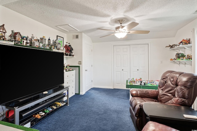 living area with dark colored carpet, attic access, ceiling fan, visible vents, and a textured ceiling