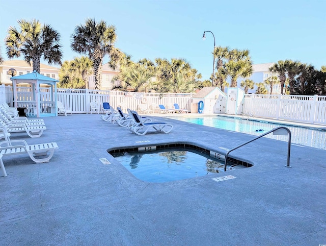 pool featuring a community hot tub, a patio area, and fence
