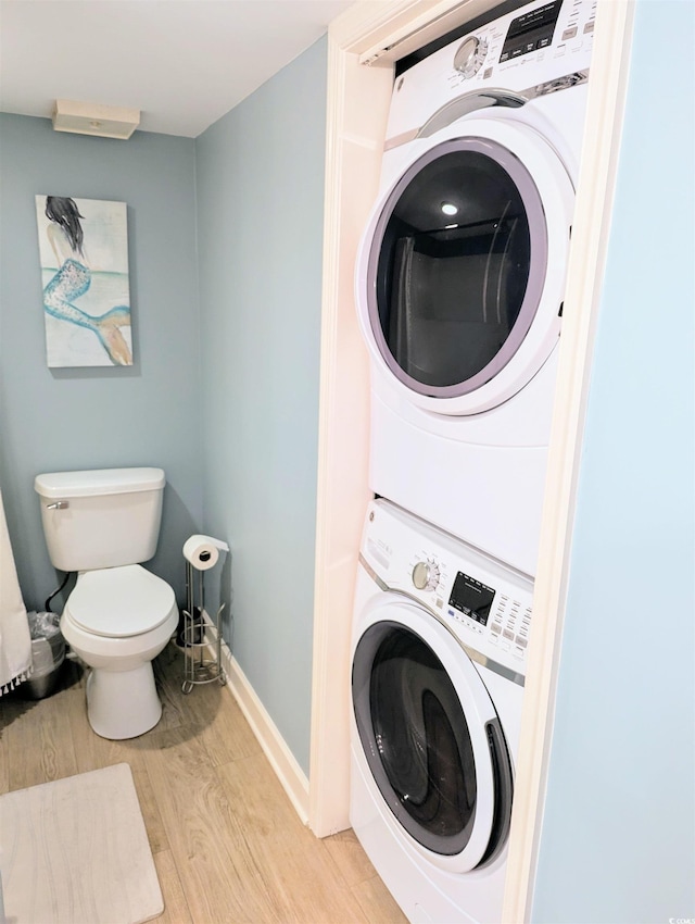 washroom featuring stacked washing maching and dryer, laundry area, baseboards, and light wood-style floors