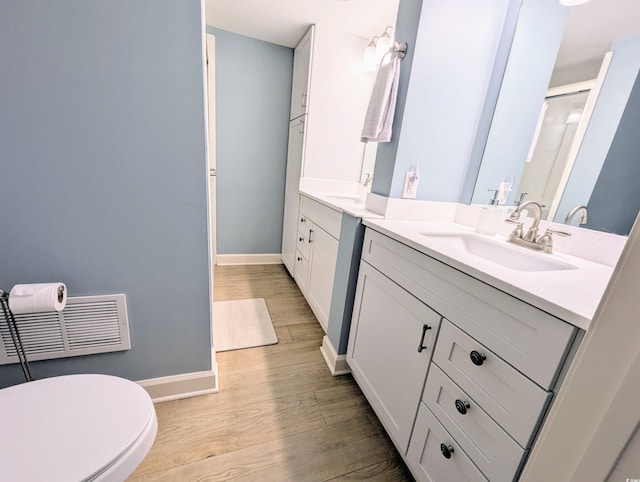 bathroom with two vanities, baseboards, visible vents, a sink, and wood finished floors