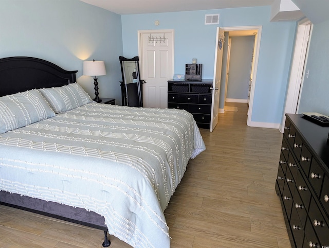 bedroom with visible vents, light wood-style flooring, and baseboards