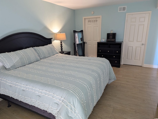 bedroom with visible vents, baseboards, and wood finished floors