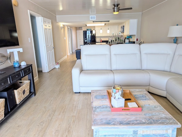 living area with light wood-type flooring, baseboards, a ceiling fan, and visible vents