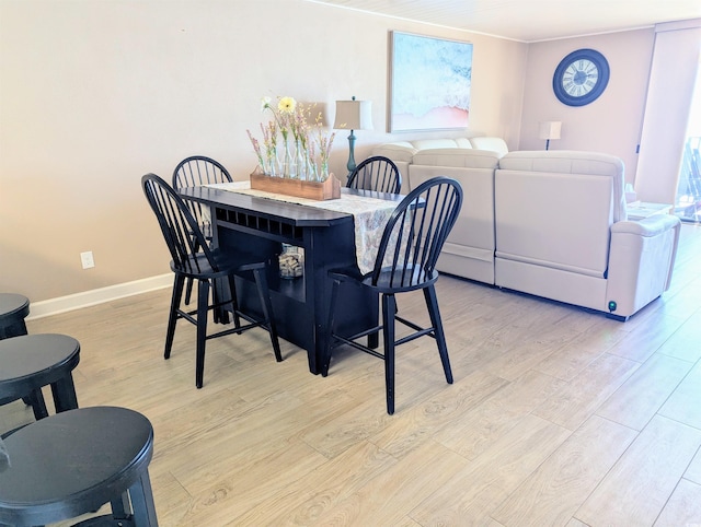 dining space featuring light wood-style flooring and baseboards