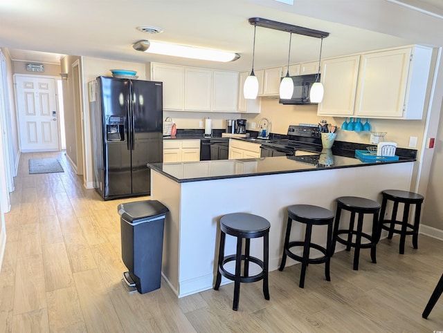 kitchen with visible vents, dark countertops, light wood-style floors, a peninsula, and black appliances