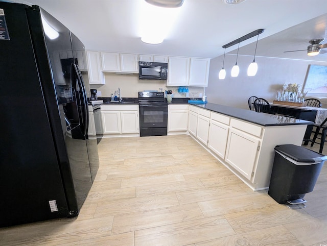 kitchen featuring dark countertops, black appliances, a peninsula, and white cabinetry