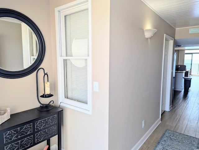 hallway with wood finished floors, baseboards, and visible vents