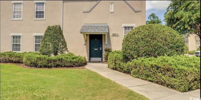 doorway to property with a lawn and stucco siding