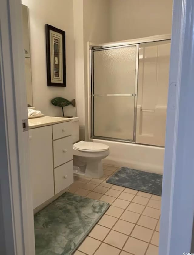 full bath featuring tile patterned flooring, vanity, toilet, and enclosed tub / shower combo