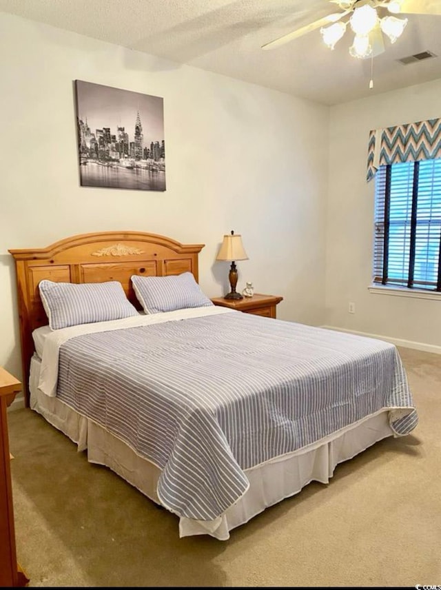 carpeted bedroom with ceiling fan and baseboards