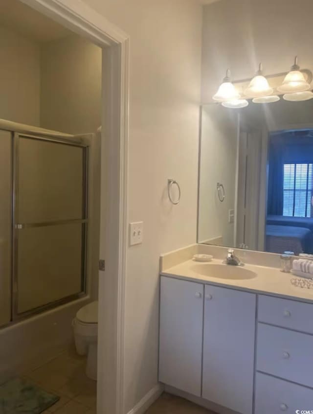 full bathroom featuring toilet, vanity, tile patterned floors, and enclosed tub / shower combo