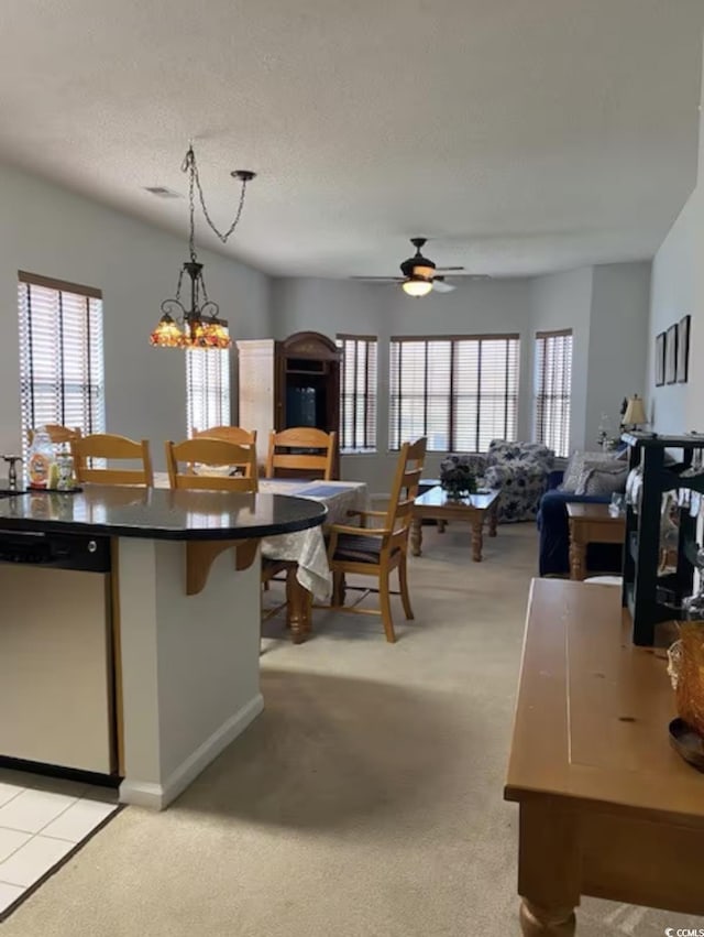 kitchen with stainless steel dishwasher, a ceiling fan, plenty of natural light, and light carpet