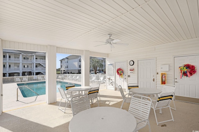 view of patio with outdoor dining area, ceiling fan, and a community pool
