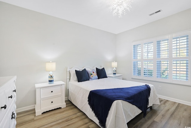 bedroom with baseboards, visible vents, and light wood finished floors