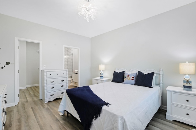 bedroom with baseboards, ensuite bath, and light wood-type flooring