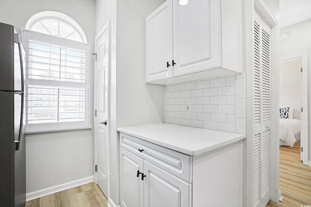 clothes washing area featuring light wood-style floors and baseboards