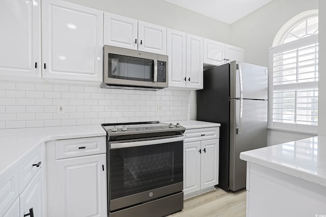 kitchen featuring decorative backsplash, stainless steel appliances, and white cabinetry