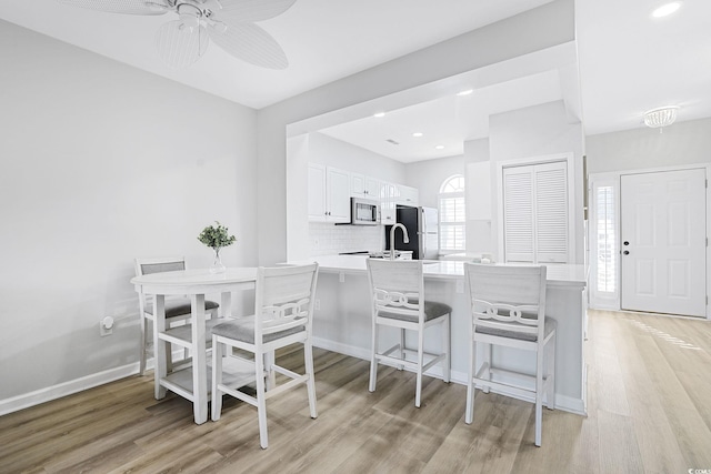 dining area with light wood-style floors, a ceiling fan, baseboards, and recessed lighting