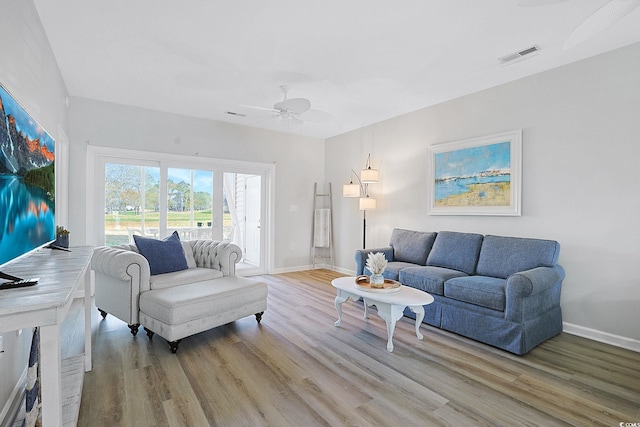 living area with baseboards, ceiling fan, visible vents, and wood finished floors
