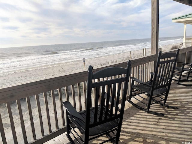 wooden terrace featuring a water view and a view of the beach