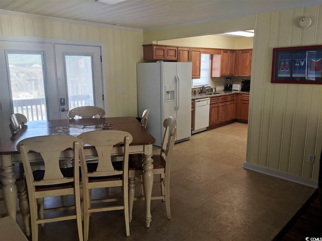 dining area featuring crown molding, wood walls, and french doors
