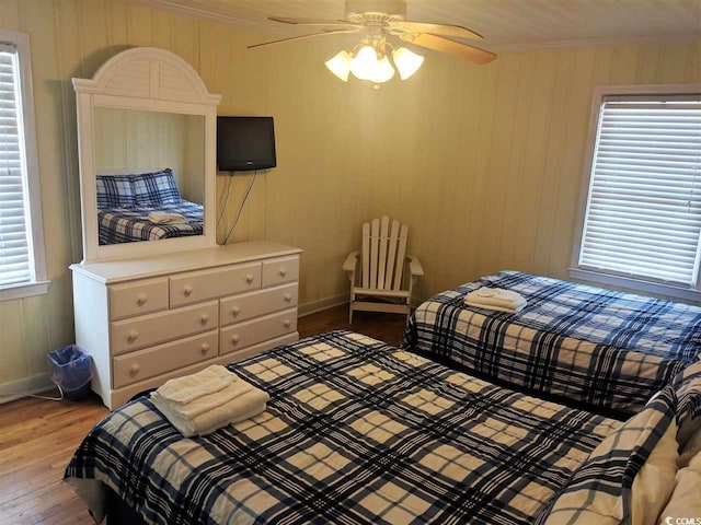 bedroom featuring crown molding, baseboards, ceiling fan, and wood finished floors