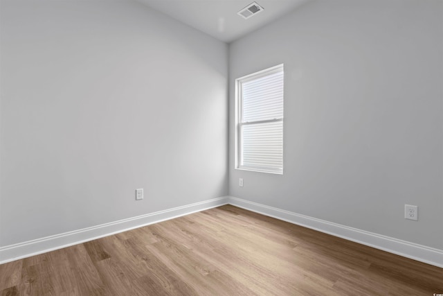 empty room featuring visible vents, baseboards, and wood finished floors