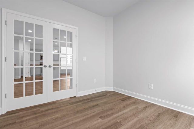 empty room with french doors, baseboards, recessed lighting, and wood finished floors
