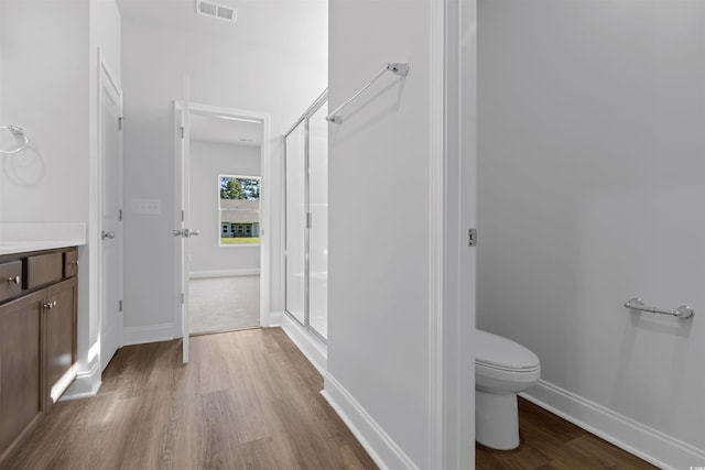 full bathroom featuring visible vents, baseboards, toilet, a shower stall, and wood finished floors