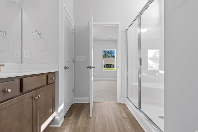 full bath with a shower stall, vanity, baseboards, and wood finished floors