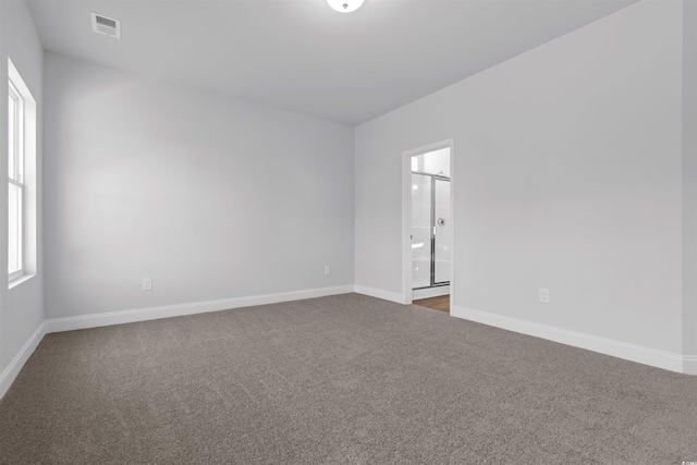 carpeted spare room featuring visible vents and baseboards