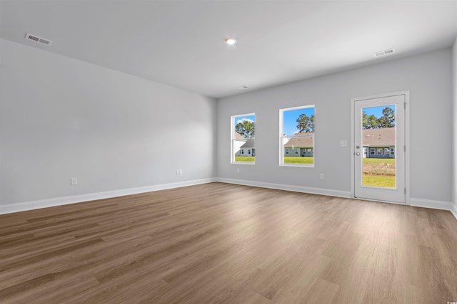 spare room featuring visible vents, baseboards, and wood finished floors