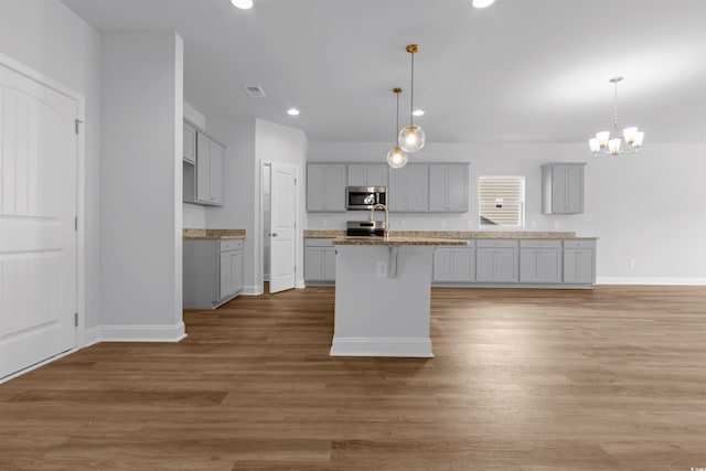 kitchen with baseboards, an island with sink, gray cabinetry, visible vents, and appliances with stainless steel finishes