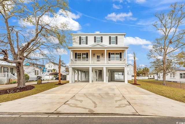 view of front of property with stairway, a front yard, driveway, covered porch, and a carport