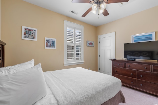 bedroom with visible vents, a ceiling fan, and light carpet