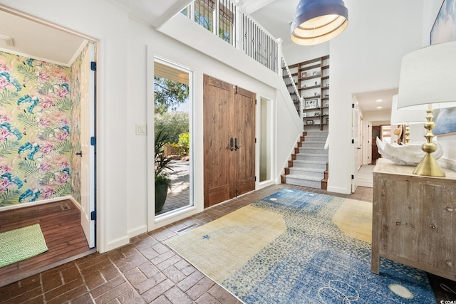entryway featuring brick floor, a towering ceiling, baseboards, and stairway