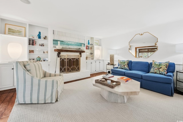 living area with built in features, wood finished floors, and a fireplace