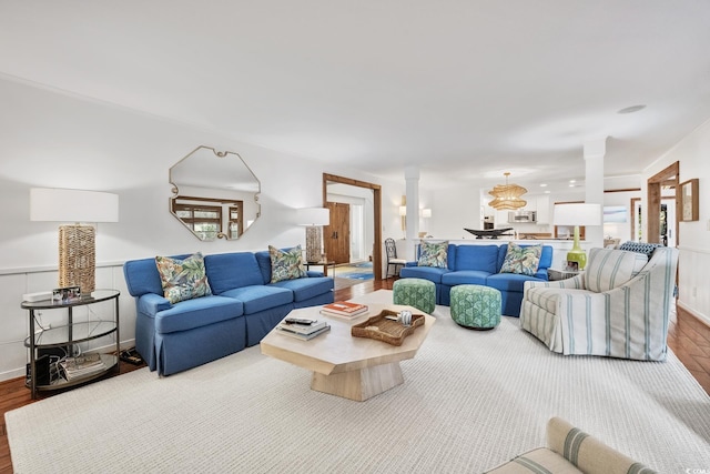 living area with decorative columns, wainscoting, and wood finished floors