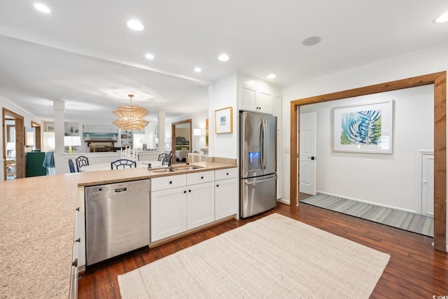kitchen featuring light countertops, white cabinets, dark wood-type flooring, stainless steel appliances, and a sink