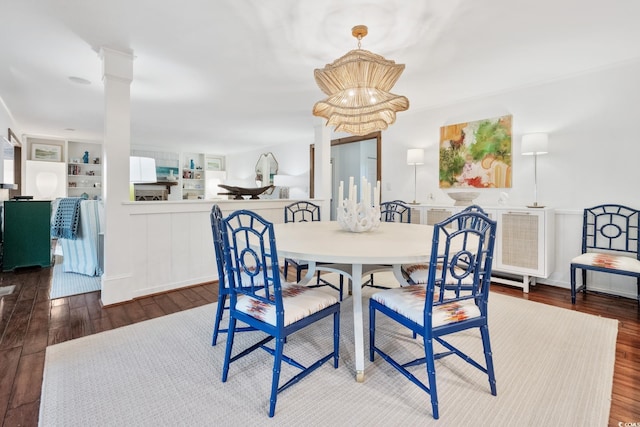 dining room with a wainscoted wall, decorative columns, and wood finished floors