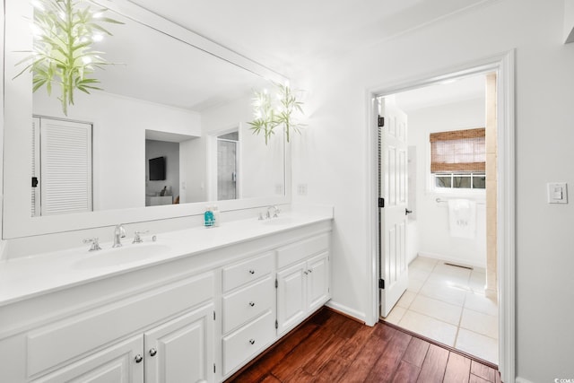 full bath with wood finished floors, double vanity, a sink, and baseboards